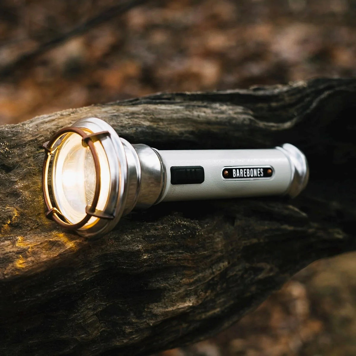 Barebones Flashlight LIV-291_Vintage_zaklamp_SlateGray liggend op een boomstronk
