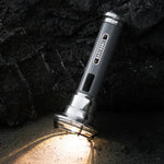 Barebones Flashlight LIV-291_Vintage_zaklamp_SlateGray schijnend naar beneden, staand tegen een rots