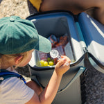 Dometic PSC19 Soft Cooler – waterdichte koeltas met top isolatie, 19 liter,in kleur Moss gevuld en geopend op het strand met een kindje met petje ernaast.