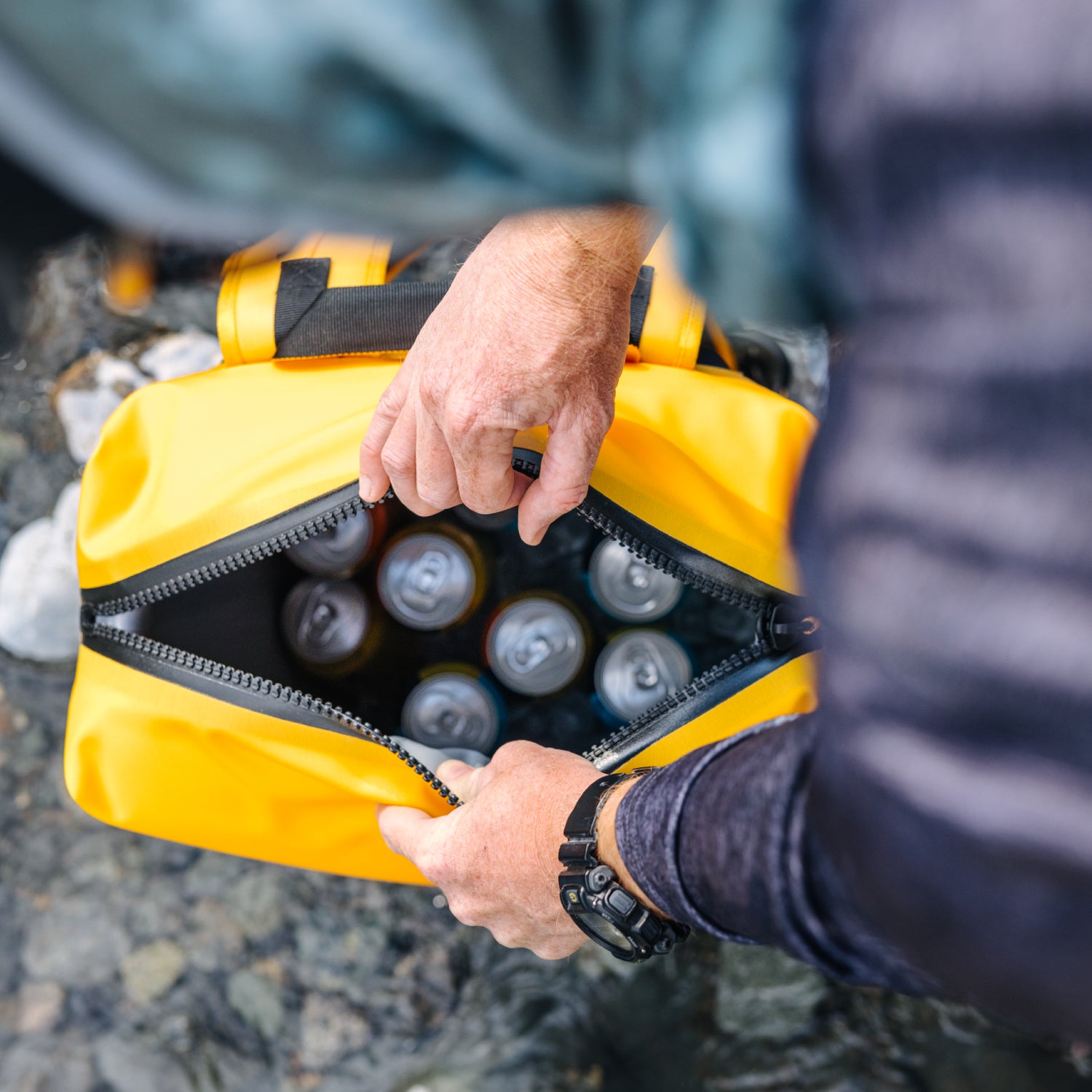 Dometic PSC22BP koelrugzak – waterdichte koeltas backpack 22L in kleur Glow geopend door een wandelaar die via de bovenzijde blikjes laat zien