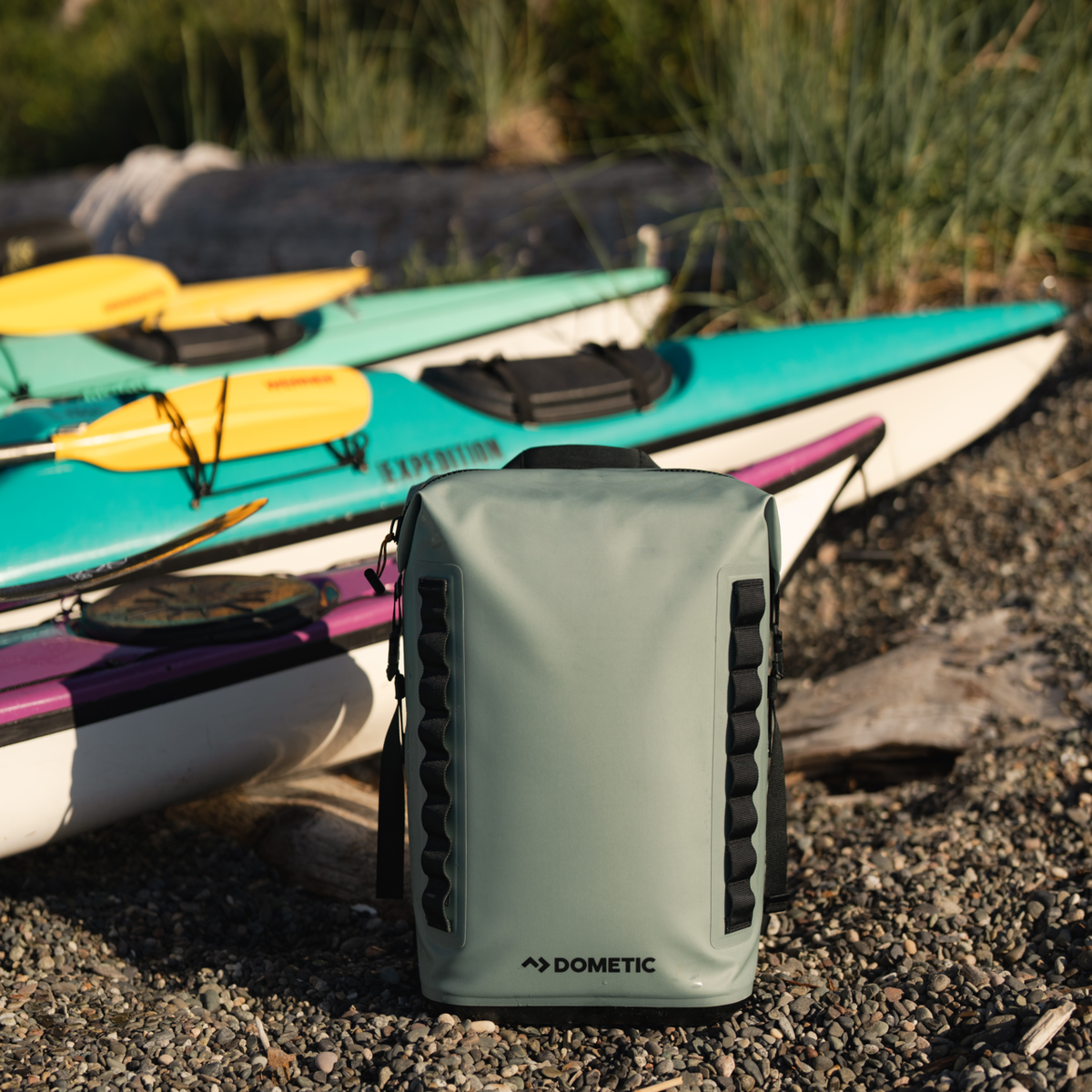 Dometic PSC22BP koelrugzak – waterdichte koeltas backpack 22L in kleur Moss, neergezet naast een aantal kano's