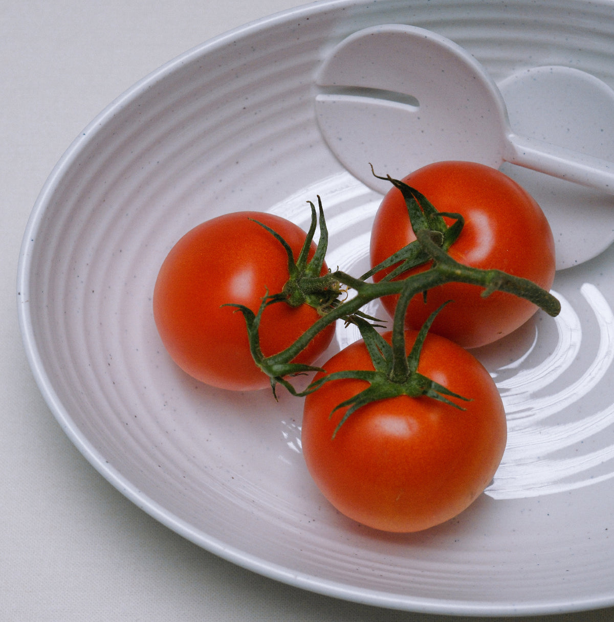Flamefield Granite Pearl salade set – 3-delig ovaal melamine met wit ribbel design ingezoomd op de slalepel en vork met drie tomaten erop