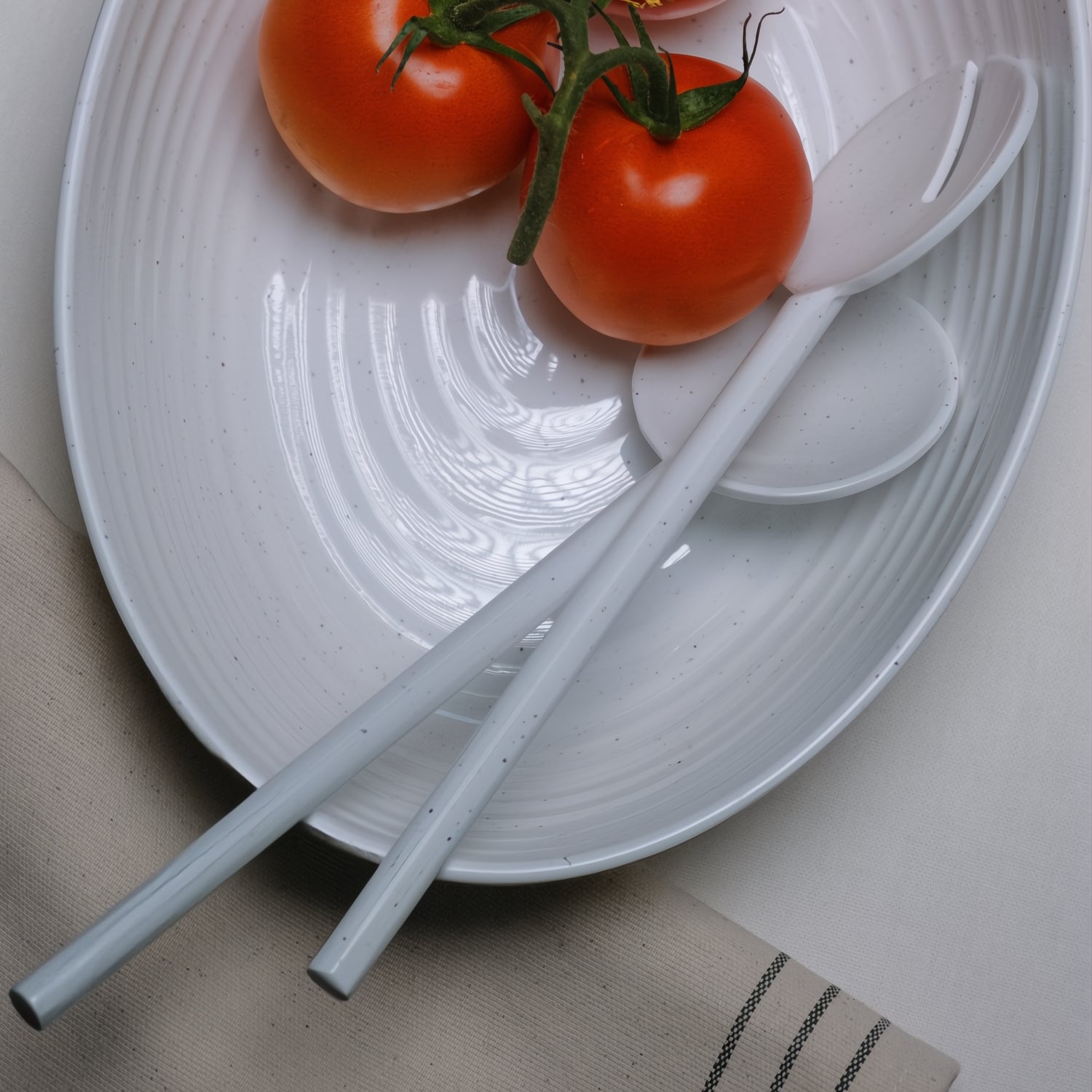 Flamefield Granite Pearl salade set – 3-delig ovaal melamine met wit ribbel design ingezoomd op de slalepel en vork met twee tomaten erop