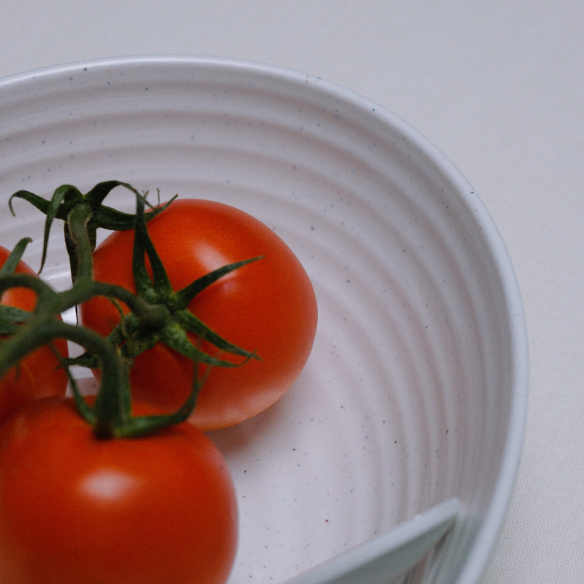 Flamefield Granite Pearl salade set met tomaten erop, 3-delig ovaal melamine met ingezoomd op het wit ribbeldesign 