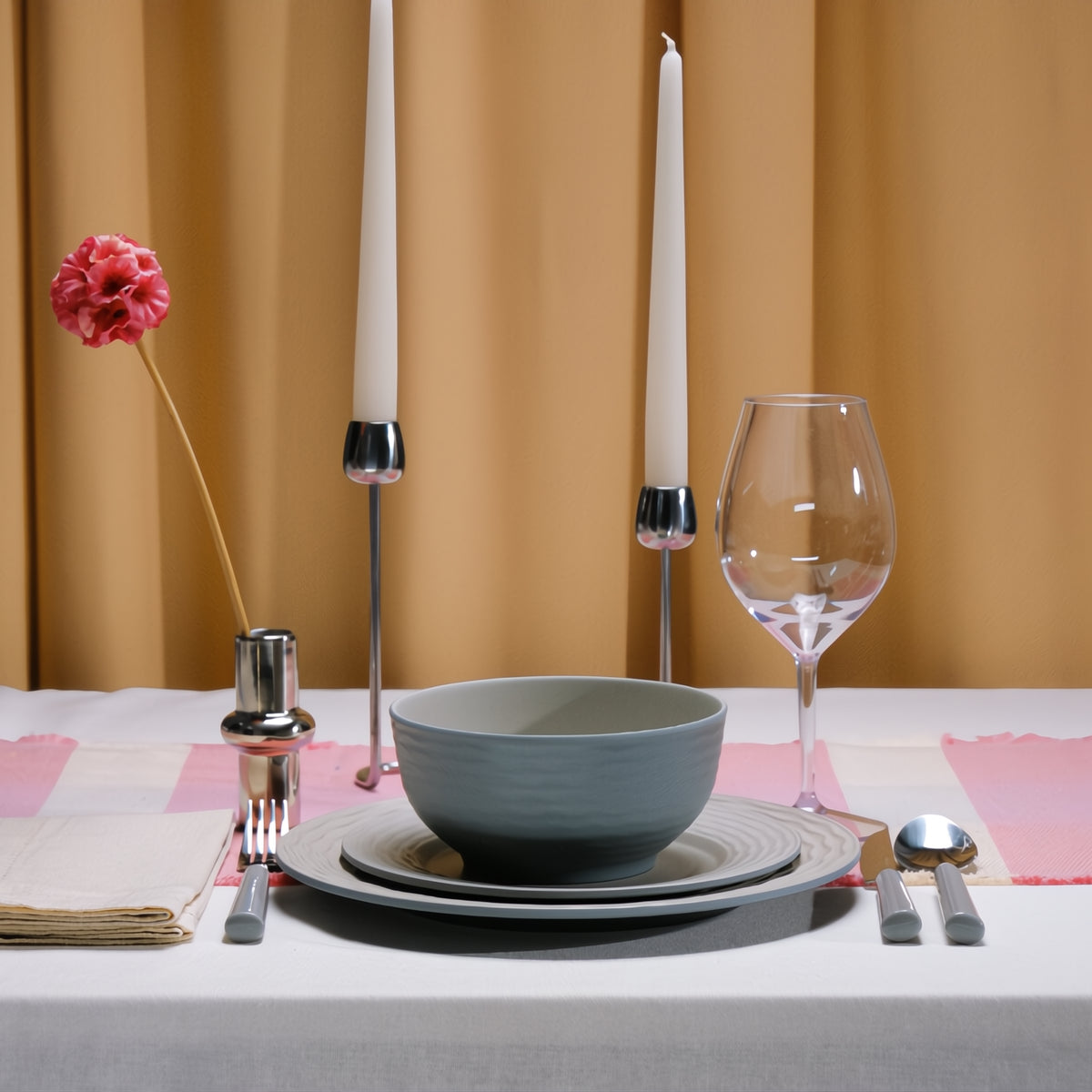 Flamefield Ripple Sand RS0112 melamine servies zand, grijs, natuur relief, in sfeerbeeld met glas wijn kaarsen en gedekte tafel met okergeel gordijn