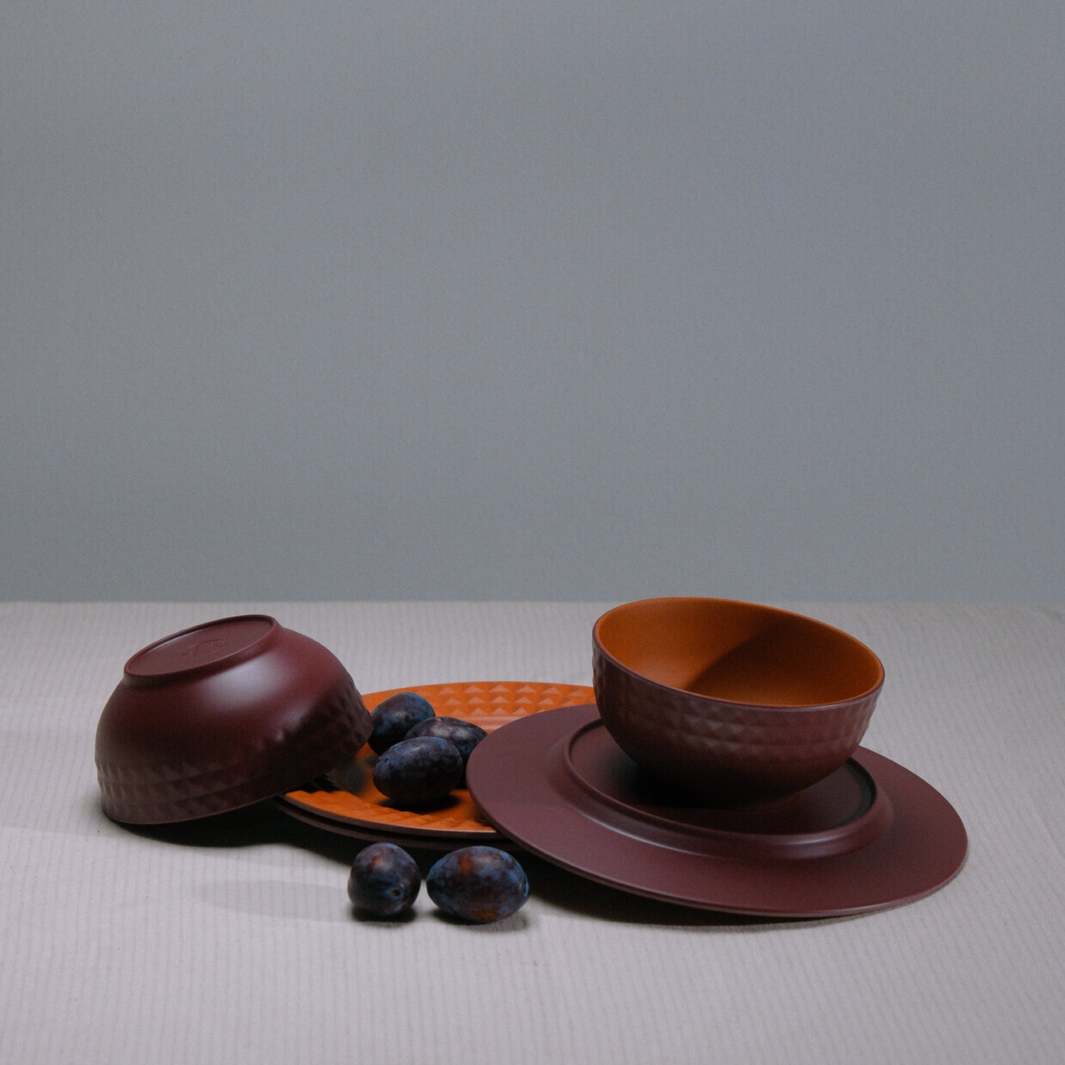 Flamefield Viva Terra melamine servies bordeaux, rood sfeerbeeld met dadels op twee borden en kommen op grijze achtergrond