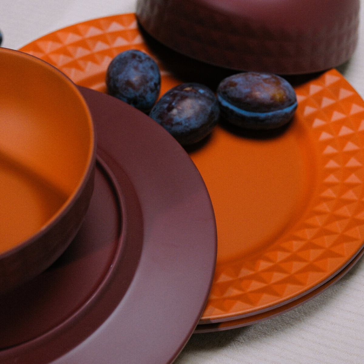 Flamefield Viva Terra melamine servies borden en kommen gemixt door elkaar in bordeaux, rood ingezoomd met dadels