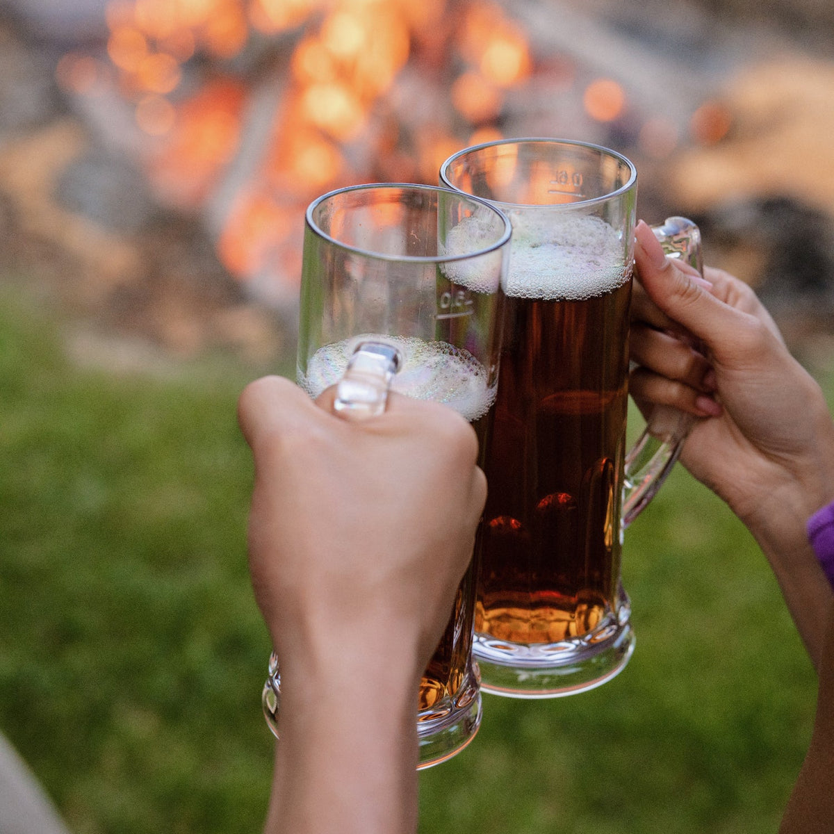 Flamefield_bierpullen_twee_tegen_elkaar_aan_proostend_bij_kampvuur