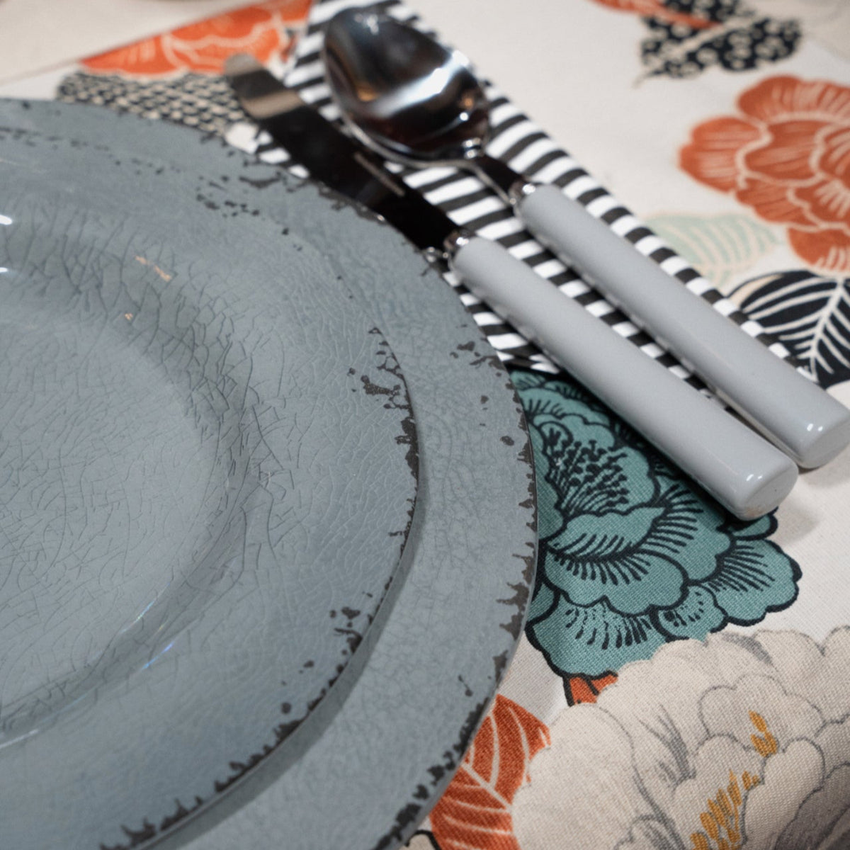 Flamefield onbreekbaar servies Moondust dinerbord ingezoomd op een tafelkleed met bloemen en grijs bestek