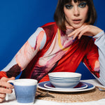 Flamefield seerbeeld van fotomodel in rood gekleurde trui met onbreekbaar servies Azure blauw met wit AZ0112 op een rieten placemate en Azure mok