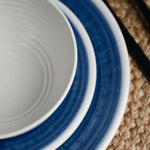 Flamefield sfeerbeeld van onbreekbaar servies Azure blauw met wit AZ0112 op een rieten placemat ingezoomd als een lijnenspel