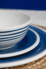 Flamefield sfeerbeeld van onbreekbaar servies Azure blauw met wit AZ0112 op een rieten placemat ingezoomd als een lijnenspel vooraanzicht