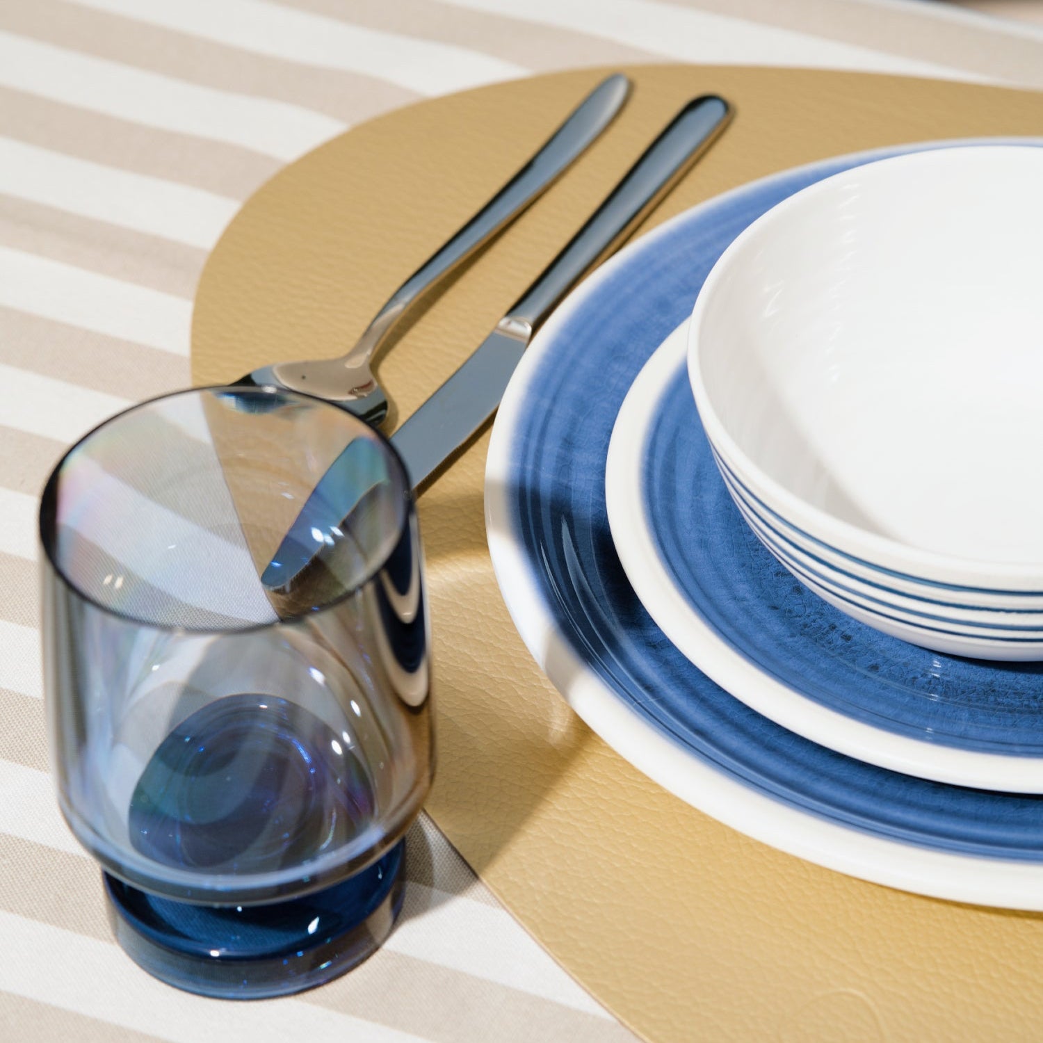 Flamefield sfeerbeeld van onbreekbaar servies Azure blauw met wit AZ0112 op een rieten placemat met Heavy base wijngas in chique blauw
