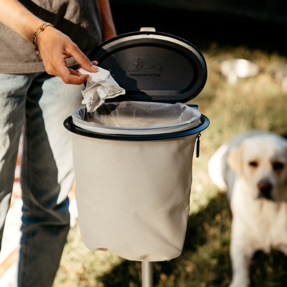 Flextrash_Small in keur Casual Creme vrouw gooit zakdoek erin met hond op de achtergrond