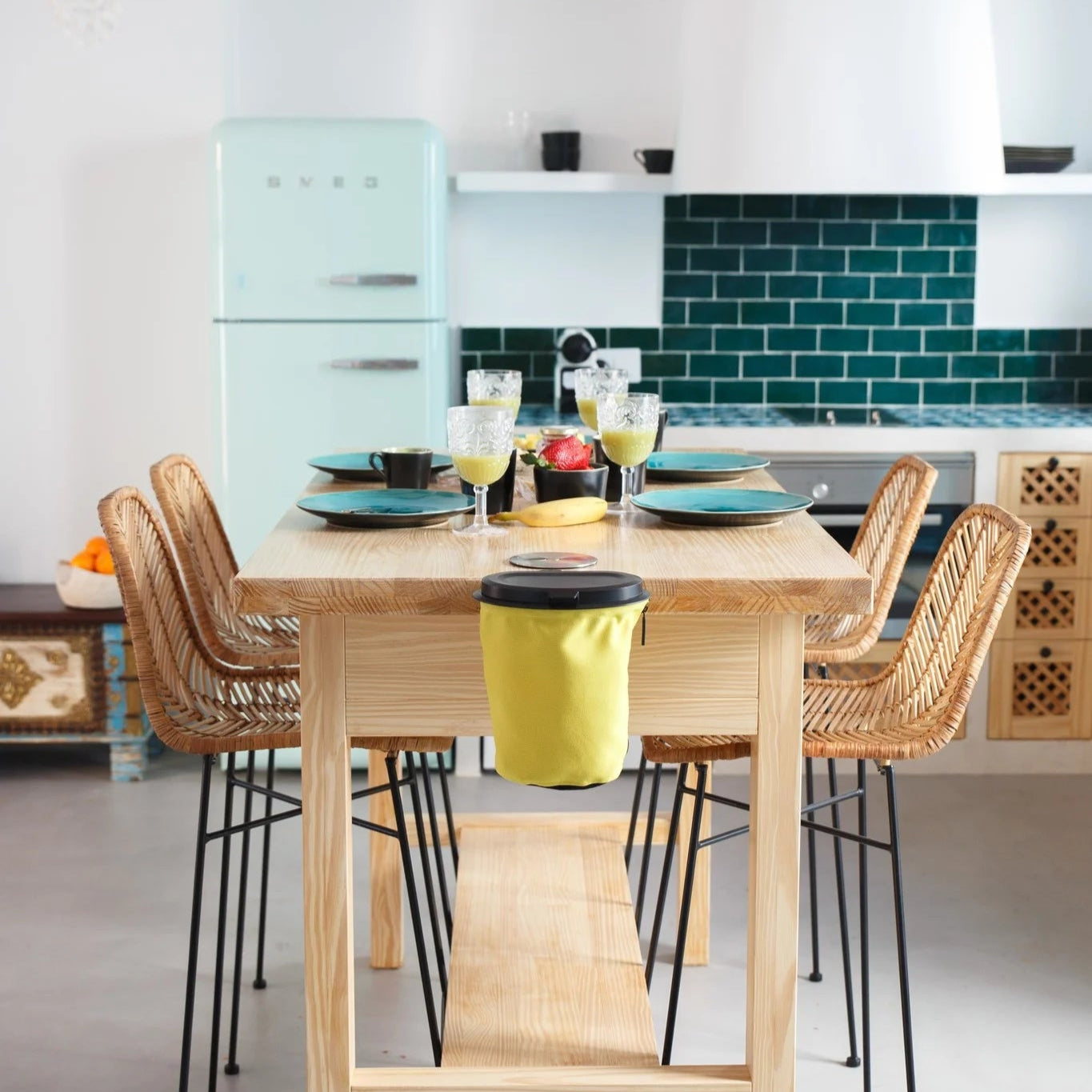 Flextrash_Table_clip_aan_een_eettafel in een sfeersetting met houten meubilair en een Smeg koelkast op de achtergrond