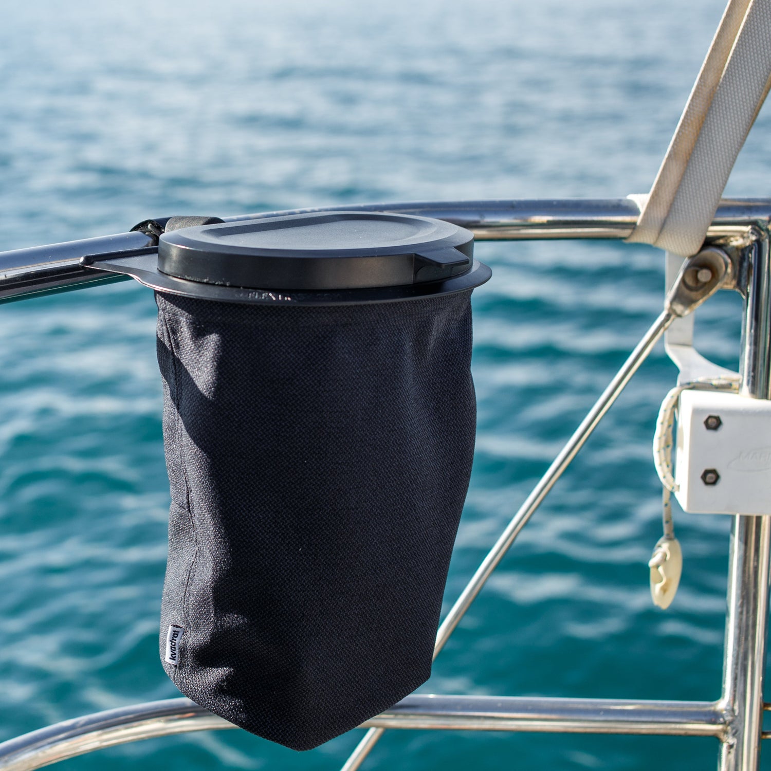 Flextrash_prullenbak_Navy Blue hangend aan de railing van een boot met water op de achtergrond