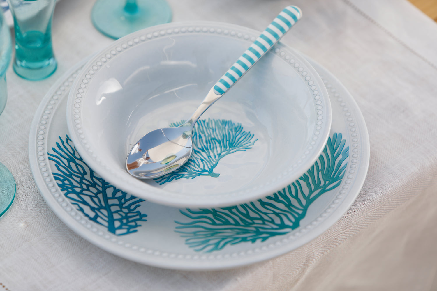 Harmony Mare Blue melamine servies - wit met koraaldecoratie en parelrand dinerbord en diep bord met lepel in sfeer beeld 