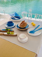 Maldivas bootservies Ivory – modern, zachte creme en onbreekbaar met opstaande rand gemixt met blauw en transparant servies van Marine Business op tafel op een luxe boot