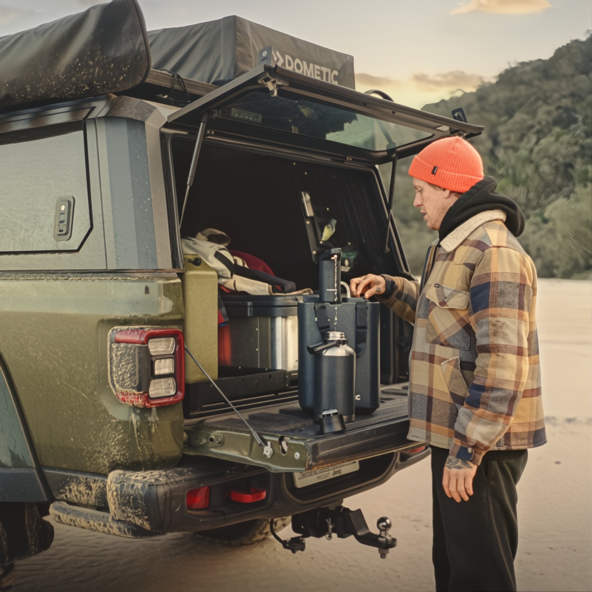Man_met_een_groene_jeep_die_de_Dometic_GO_Hydration_Water_Faucet_en_waterjug_in gebruik
