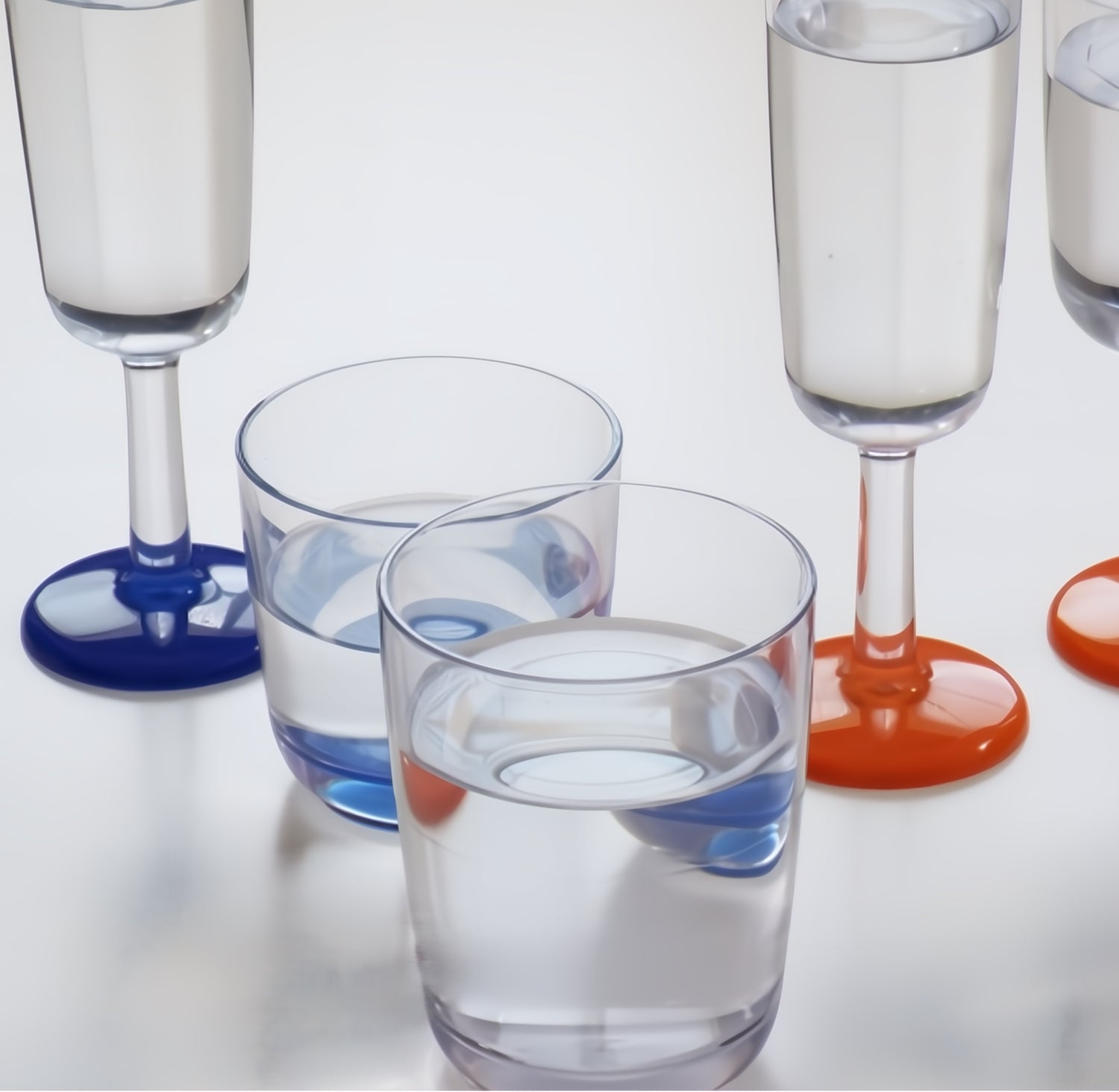 Marc Newson highball waterglas 425 ml – onbreekbaar Tritan met antislip en witte bodem, gevuld met water, samen met het waterglas, en chamapgne flutes in navy blue en met oranje voet.