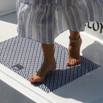 Marine business Deurmat blauw-wit ruitpatroon met ankers op een boot met een vrouw die met haar blote voeten met rood gelakte nagels erop stapt