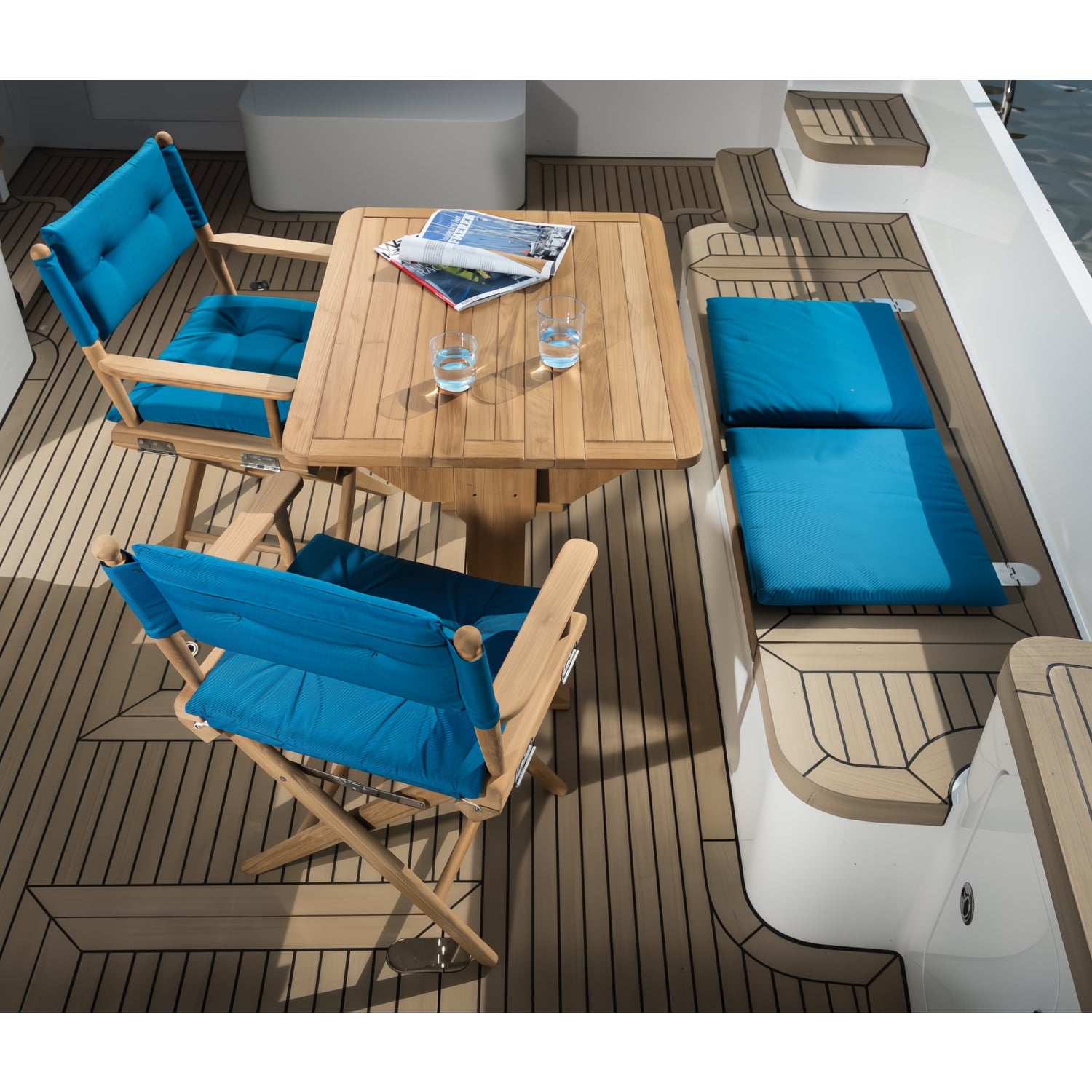 Regisseursstoel_I_deluxe_-_geolied_teak_met_navy_kussen met forza blauwe kussens sfeersetting op luxe boot op het water