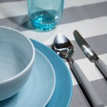 SB0112 Flamefield onbreekbaar servies Shades of Blue ingezoomd met bestek en blauw glas op een gestreept tafellaken