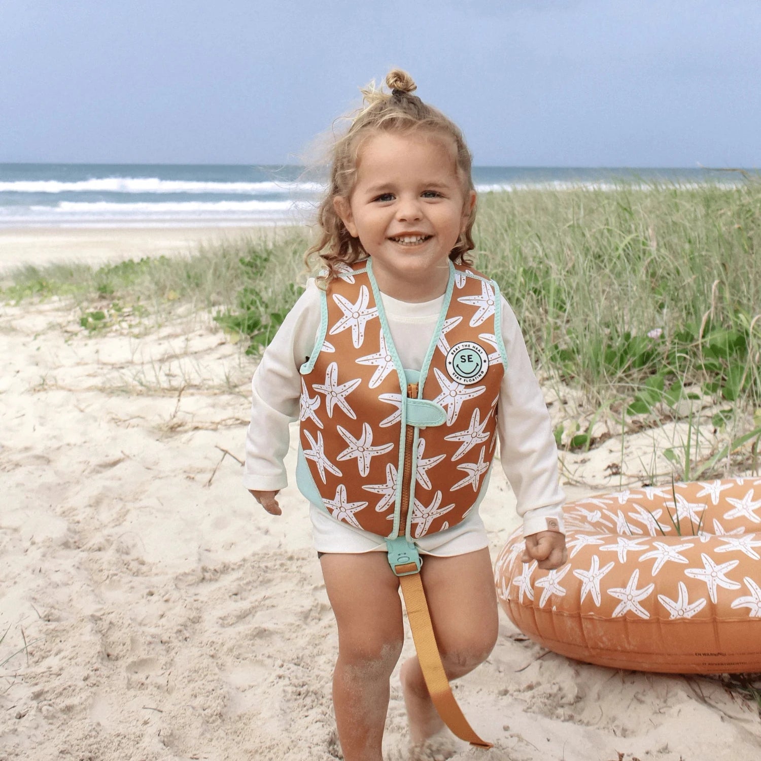 Seastar | Oranje Zwemvest 3–6 jaar met zeesterren met een kind die op het strand loopt