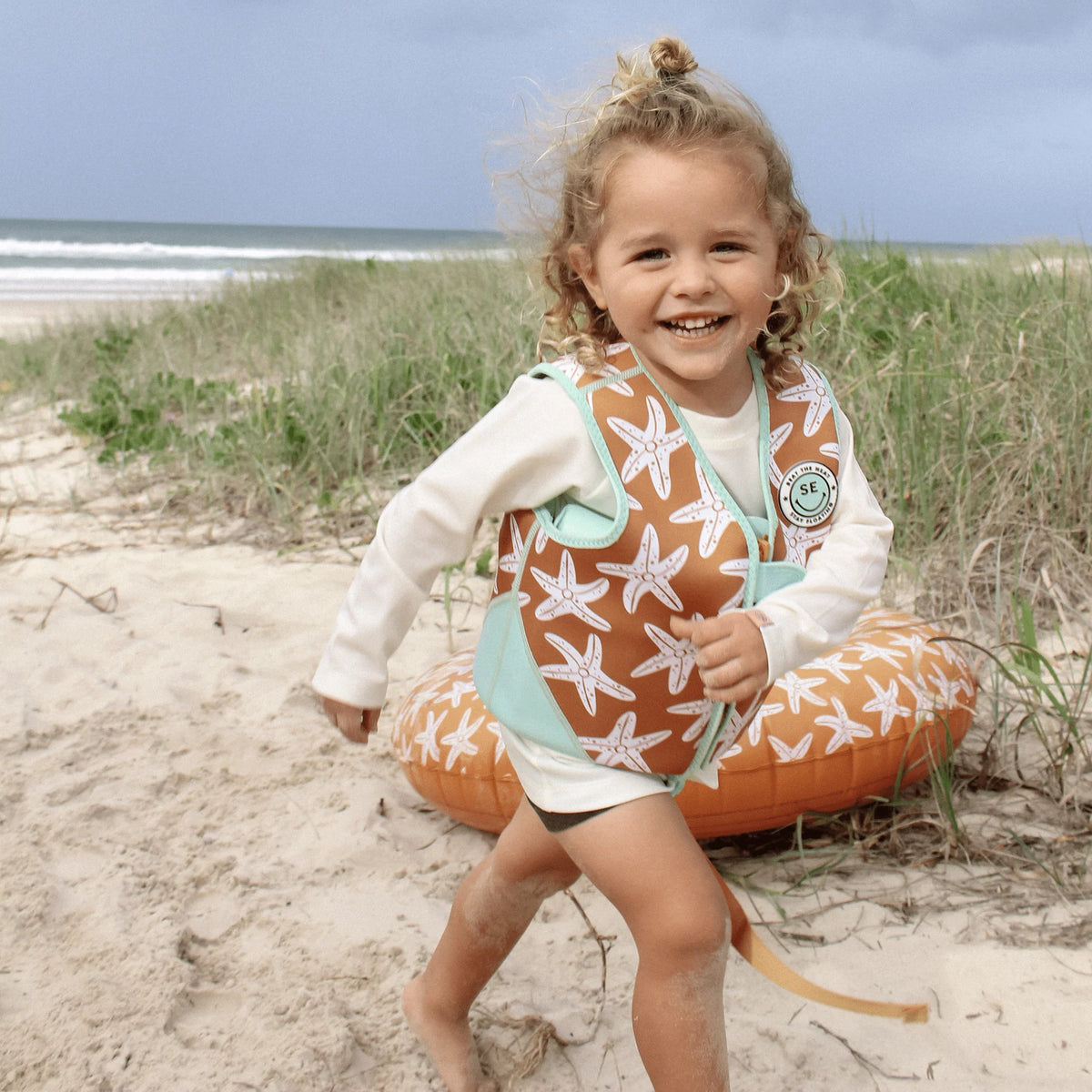 Seastar | Oranje Zwemvest 3–6 jaar met zeesterren met een kind op het strand