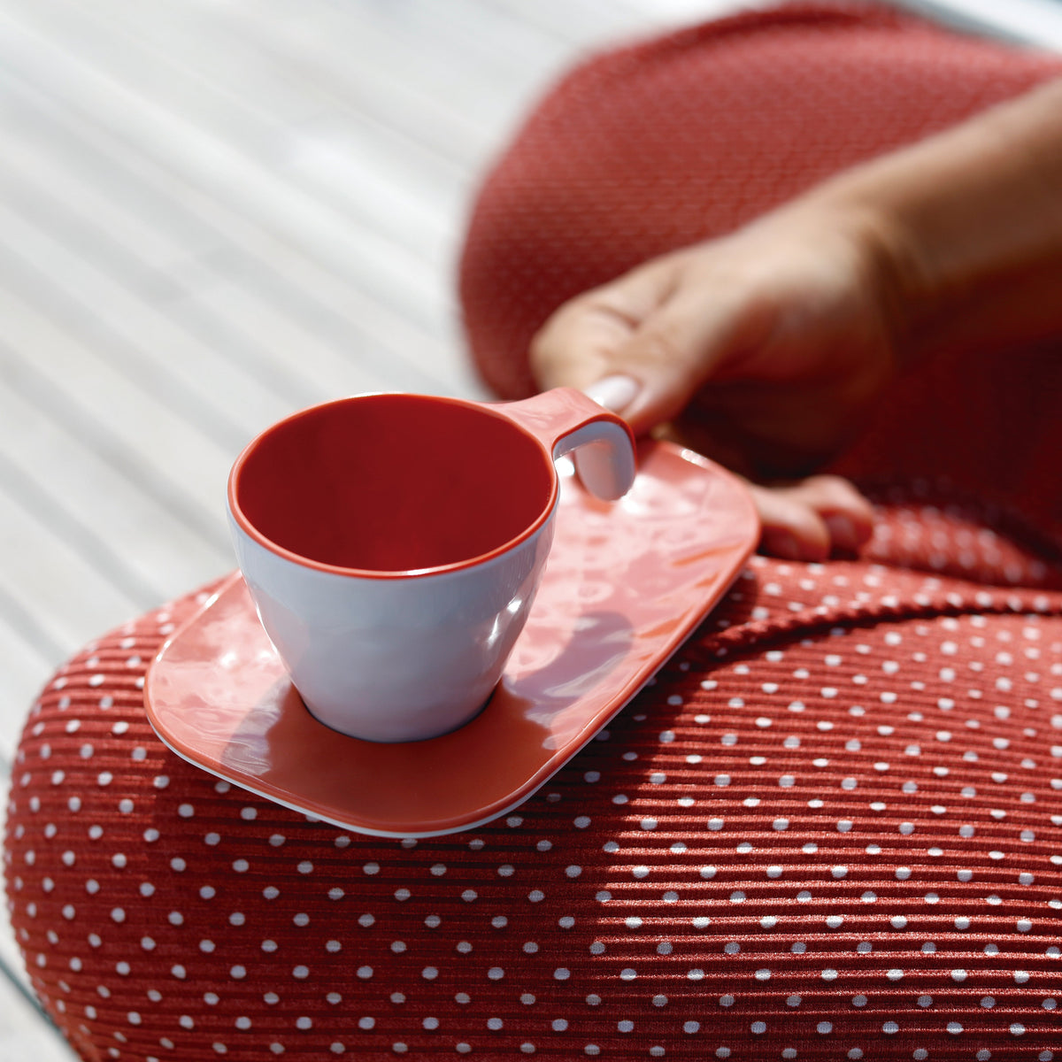 Summer Coralespresso kopje en schotel op been van vrouw die ene coralmet witte stippen broek draagt