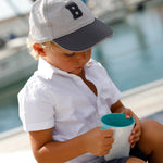 Summer serveercollectie mok acqua in handen van jongen met pet