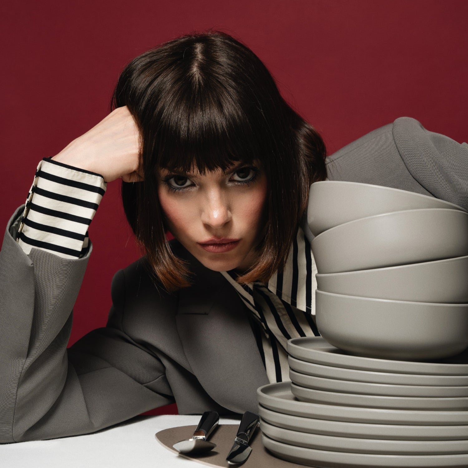 Vrouwelijk model met hand onder haar hoofd met Flamefield serviesset Pebble Sky – 12-delig, mat grijs melamine set.
