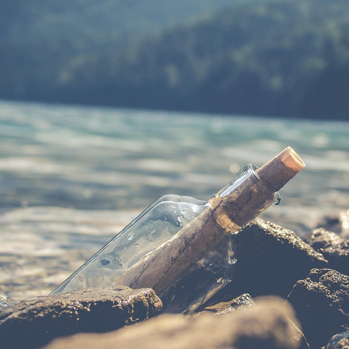 flessenpost fles met brief erin op rots aan zee als afbeelding voor ons retourbeleid